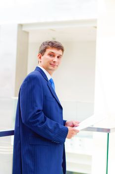 Smiling business man on the balcony, holdings reports