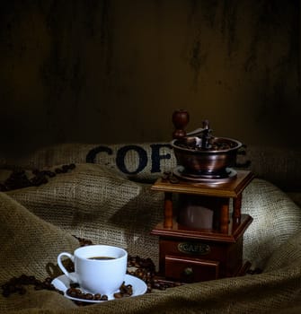 Coffee Mill with beans, cup and burlap. still life