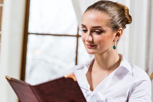 portrait of a nice lady at the restaurant, choosing dishes from the menu
