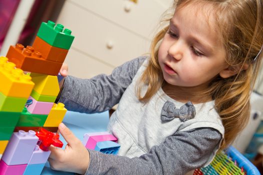 Little girl is playing with building bricks 