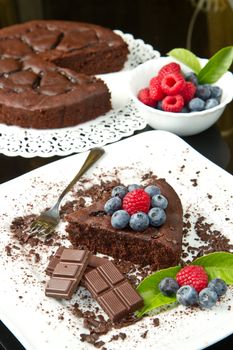 chocolate cake with fresh berry on white dish and black background