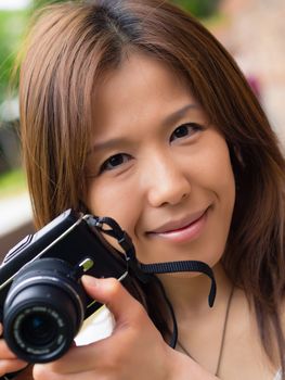 A young Japanese girl photographer holding up her compact digital camera