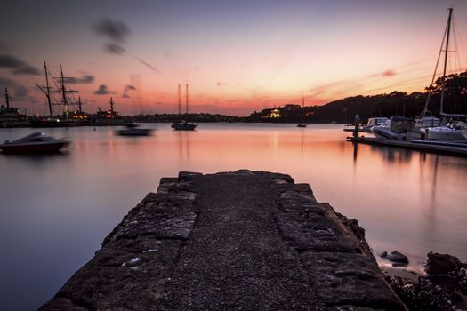 A beautiful orange sunset with an old, broken stone jetty.