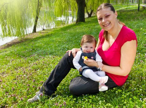 Mother holding daughter outdoors smiling