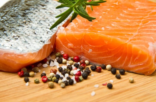 Fresh salmon fillet on wooden board with pepper and rosemary