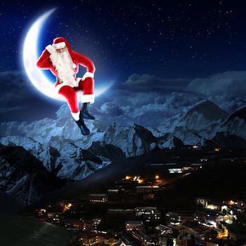 photo of santa claus sitting on the moon with a city and mountains below