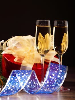 New Year's still life with glasses of champagne. Decorations and ribbons on a bright color background