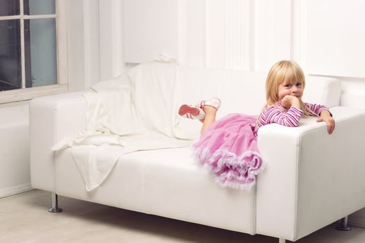 Little cute girl posing happily on sofa