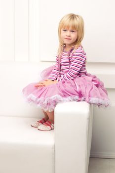 Little cute girl posing happily on sofa