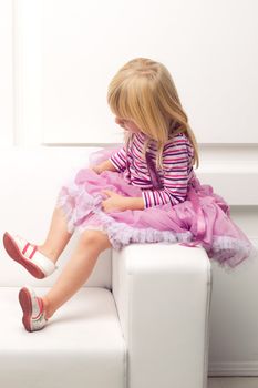 Little cute girl posing happily on sofa