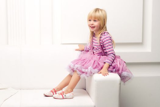 Little cute girl posing happily on sofa