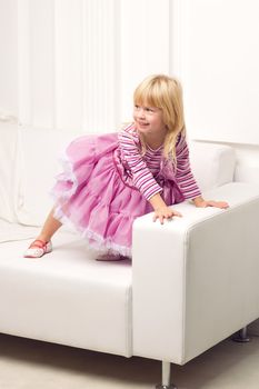 Little cute girl posing happily on sofa