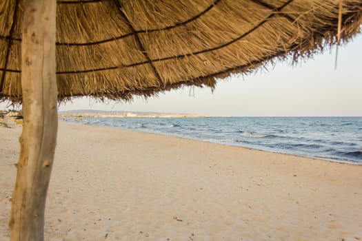 Sun shade made of straw and log on Hammamet beach with beautiful white sand along the coast of the Mediterranean sea