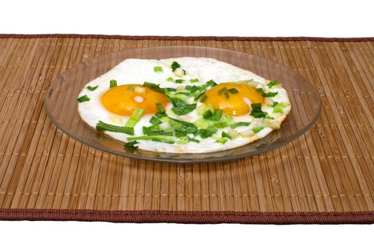 Fried eggs with green onions on a bamboo mat.