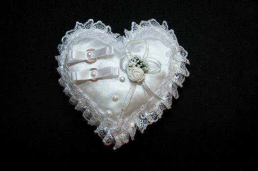 Two wedding rings in a heart-shaped pillow