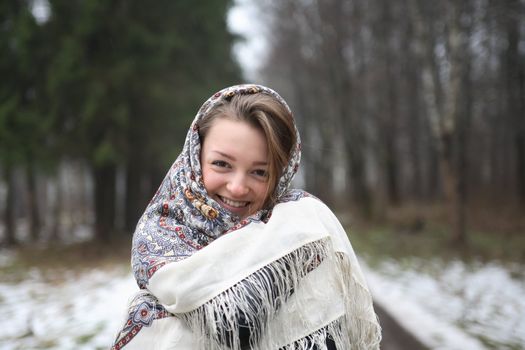 Beautiful young russian girl wearing traditional headscarf on forest background