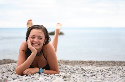 Beautiful young teenage girl lying on beach after swimming