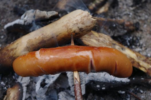 a sausage grilled on a camp fire