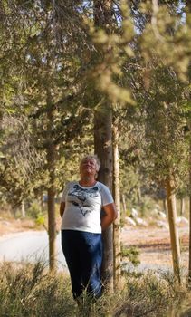 Casual portrait of happy mature woman against a background of pine trees.