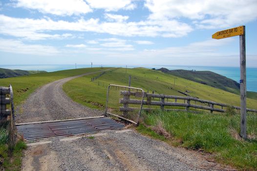 Gravel road and farm fence with direction sign, Banks Peninsula, New Zealand