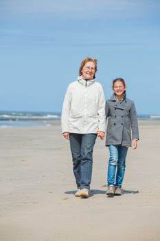 Beautiful girl and her grandmother walking on the beach. Holland