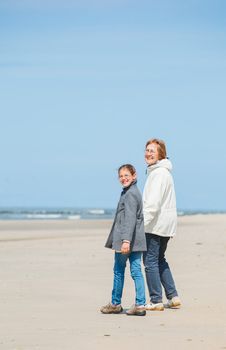 Beautiful girl and her grandmother walking on the beach. Holland