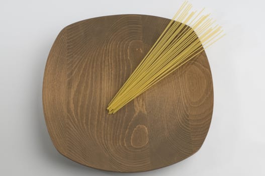 Naturel wooden plate with raw spaghetti