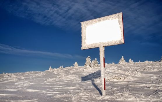 mountain winter landscape with empty billboard and blue sky