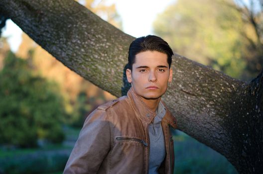 Handsome young guy in fall (autumn) outdoors in nature, at dusk