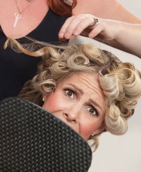 Frightened blond white female with mirror in hair salon