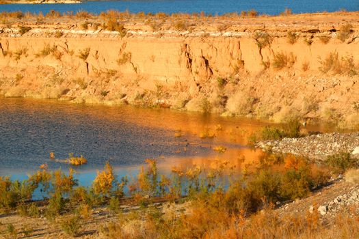 Evening sunlight creates striking colors on the rocky shoreline of Lake Mead in Nevada.