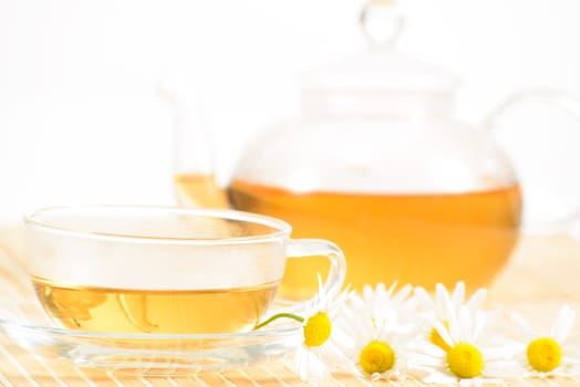 A teacup and a teapot with herbal chamomile tea