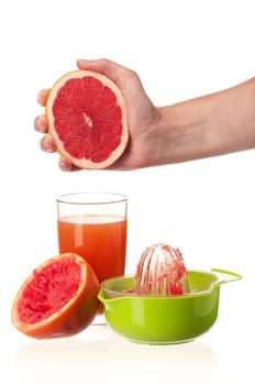 Glass of fresh grapefruit juice, juicer and hand with half of grapefruit on white background