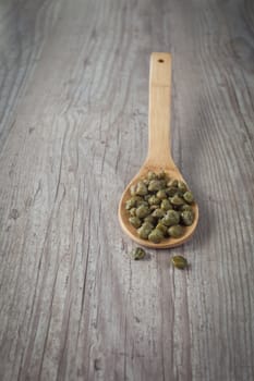 Bunch of fresh capers on a wooden spoon