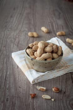 Bunch of peanuts in a bowl on wooden table