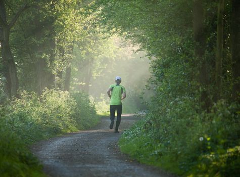 Older woman running into distance on countryside path