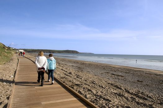 mother and daughter strolling along the beach boardwalk in Youghal county Cork Ireland