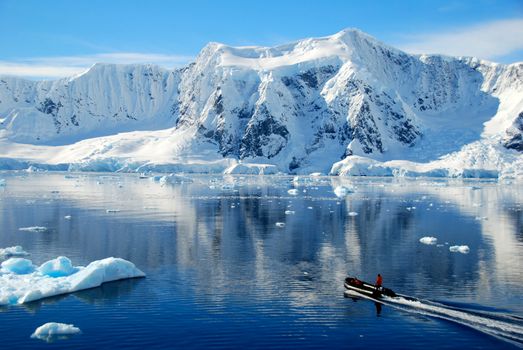 boat dwarfed by antarctic mountains