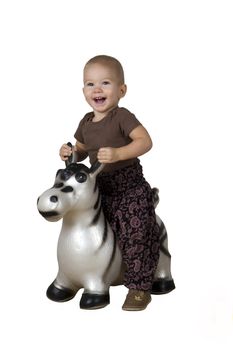 happy child (1.5 years) riding on an inflatable horse on a white background