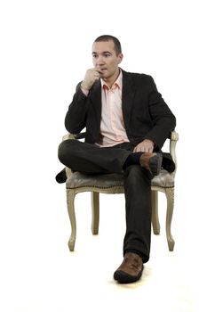 man sitting in a chair in a pose of "foot-on-foot" on a white background