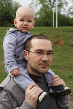 Father and son on a walk in the park.baby sitting on the shoulders of a man