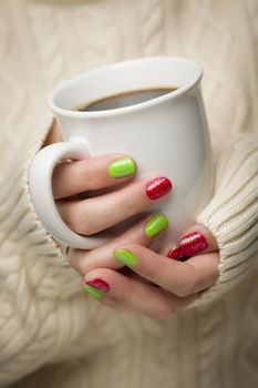 Woman in Sweater with Seasonal Red and Green Nail Polish Holding a Warm Cup of Coffee.