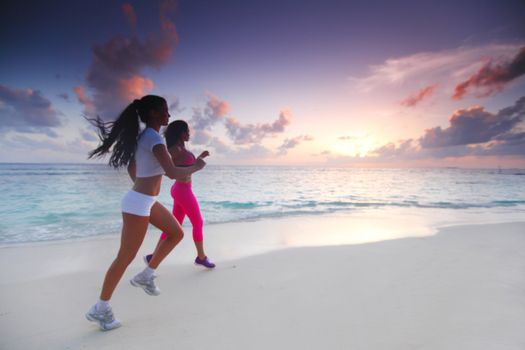 Fitness sport women running on beach at sunset