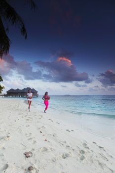 Fitness sport women running on beach at sunset