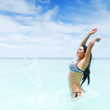 Cheerful pretty young woman splashin in sea