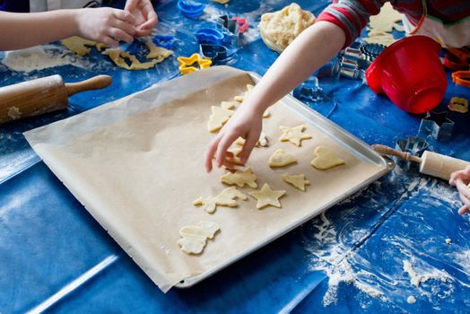 Detail of child's hands cutting Christmas cookies