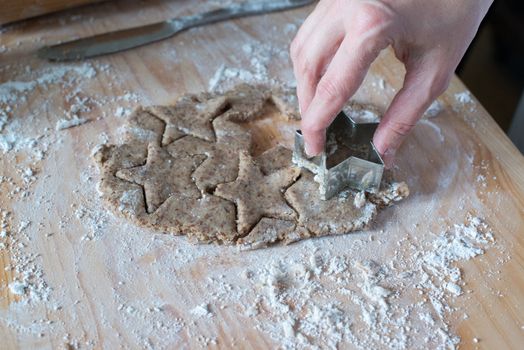 Cutting homemade Christmas cookies dough with star shape
