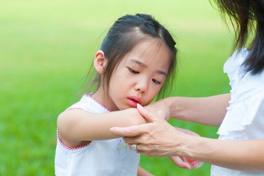 Mother checking wound to her daughter at outdoor park
