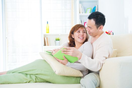 Asian couple enjoying their reading on sofa, indoor home