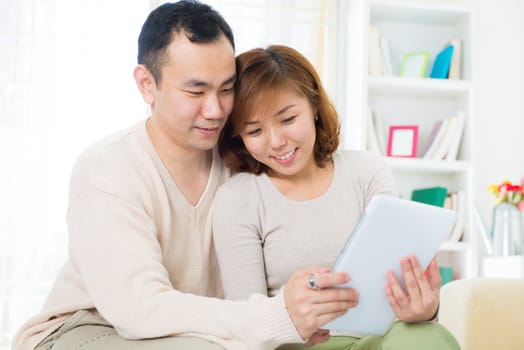 Asian couple using digital tablet computer at home
